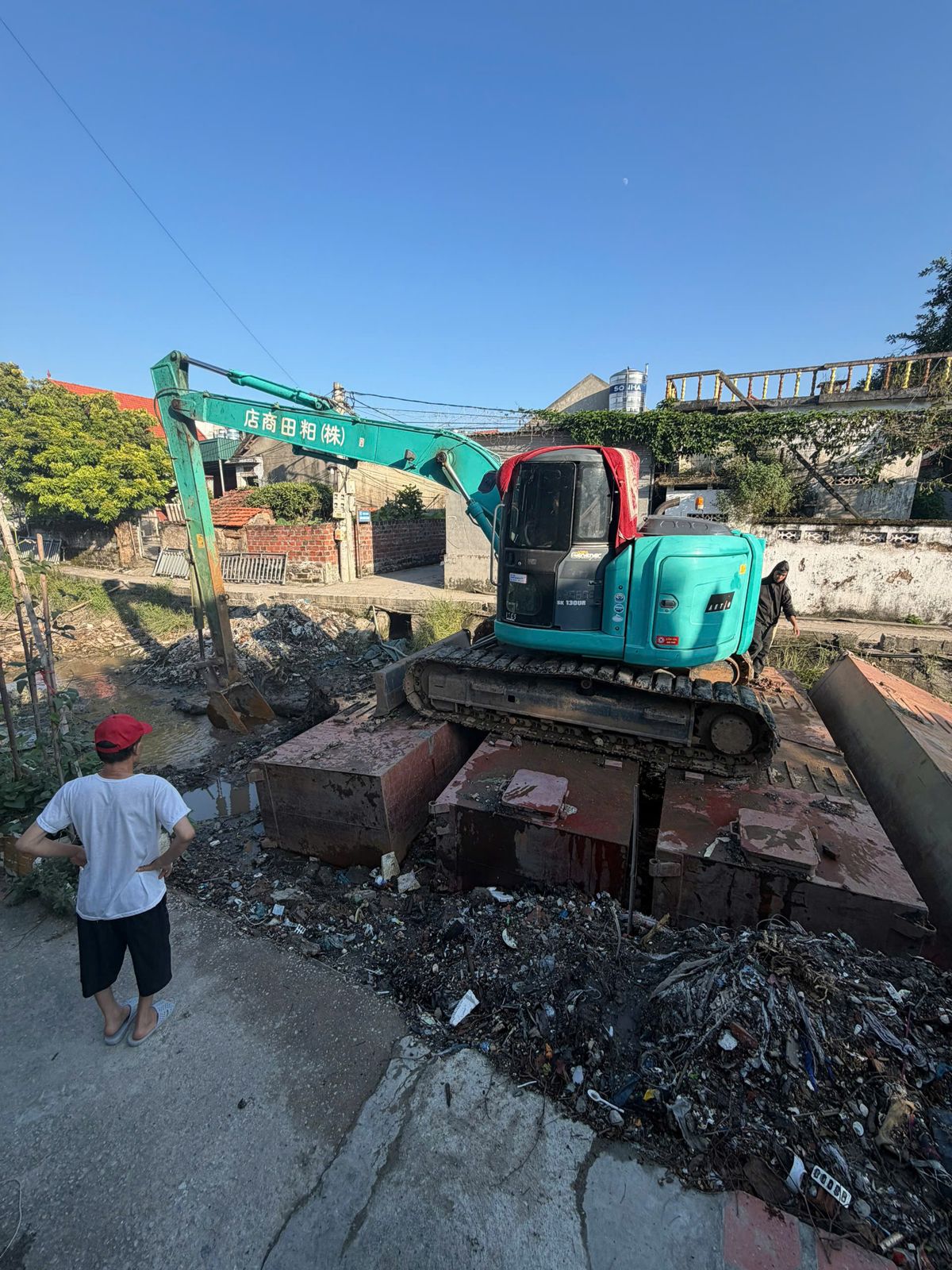 Máy xúc Kobelco SK130UR đặt phao nổi nạo vét kênh trong khu dân cư